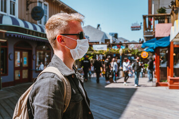 A masked man walks along Pier 39 between shops. San Francisco, USA - 17 Apr 2021