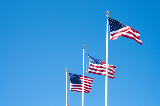 Three American flags against a blue sky