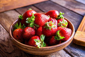 Strawberries in earthenware on an old wooden table. Cooking in the kitchen.