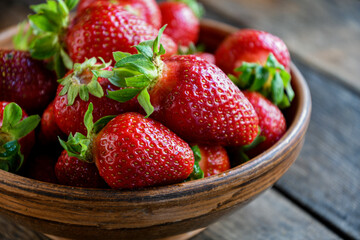Strawberries in earthenware on an old wooden table. Cooking in the kitchen.
