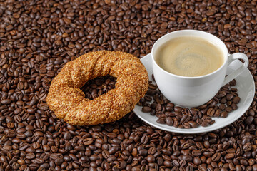 Coffee cup and simit sesame bagel on beans background with copy space