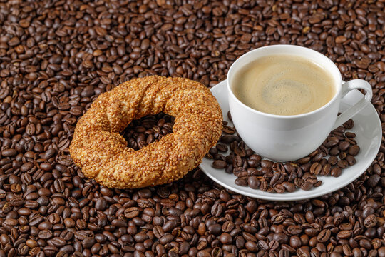 Coffee cup and simit sesame bagel on beans background with copy space © BarTa