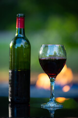 vertical camp fire table with one glass red wine and bottle. Intentional soft focus rest of scene. Low key, room for copy