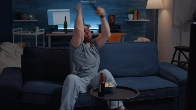 Football sport watching game late at night eating popcorn, cheering beer bottle for favourite winner team. Man enjoying championship entertainment match soccer fan looking at competition on television