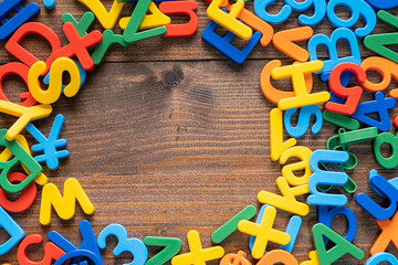 Top view of colorful plastic letters and numbers on wooden background