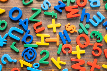Top view of colorful plastic letters and numbers on wooden background