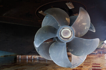 The bottom of a ship supported in dry dock with azimuth propulsion and twin propellers aft.