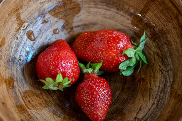 Three fruits of red, ripe strawberries in a ceramic bowl