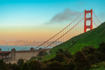 Obraz premium The top of the Red Golden Gate Bridge in the clouds photographed from a hill at sunset, San Francisco