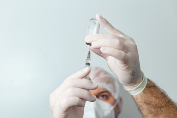 Médico preparando uma seringa com vacina em primeiro plano.