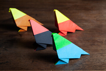 A cute colored origami birds on a rustic wooden surface.