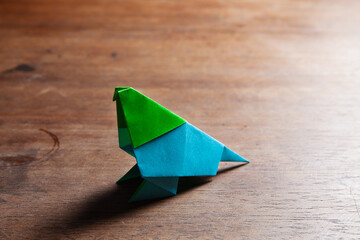 A cute colored origami birds on a rustic wooden surface.