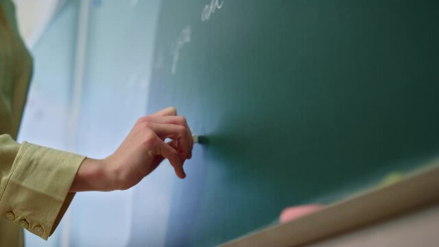 Teacher drawing on blackboard. Schoolteacher hand writing on chalkboard 