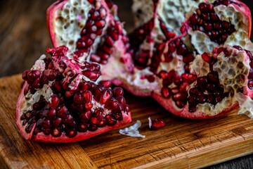 Sliced, peeled pomegranate fruit lies on a kitchen board on a wooden table.