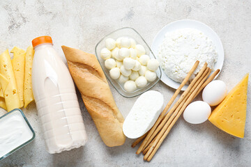 Different dairy products, bread and grissini on light background