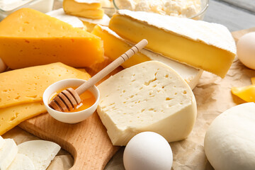 Tasty cheeses and honey on table, closeup