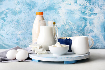 Different dairy products and chicken eggs on color background