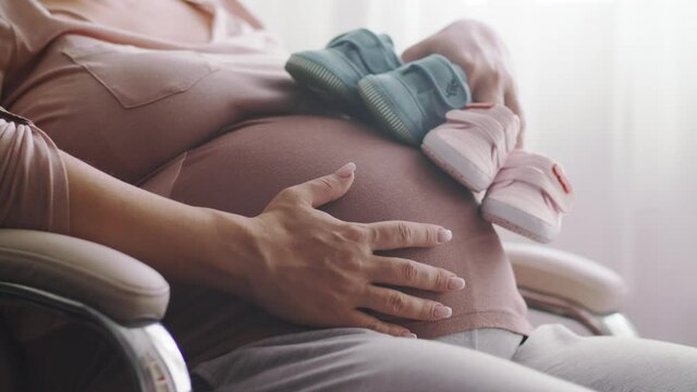 Happy pregnant woman expecting  twins. Pregnant woman feeling happy at home while taking care of her child. Pregnant woman resting alone at home strokes touches her big belly, close up. Slow motion