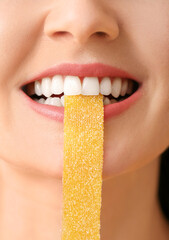 Beautiful young woman with sweet candy in mouth, closeup