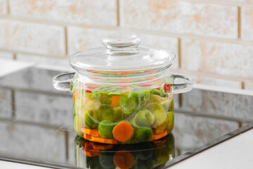 Stylish cooking pot with vegetables on stove in kitchen