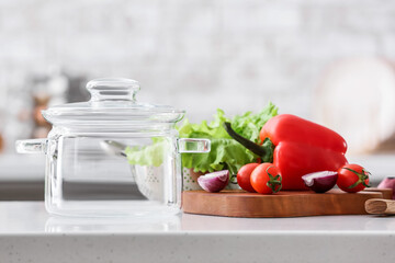 Stylish cooking pot and fresh vegetables on table in kitchen, closeup