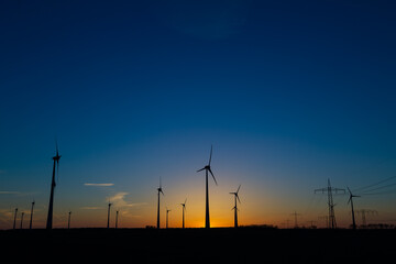 viele Windräder bei Sonnenuntergang stehen auf einem Feld und produzieren Strom