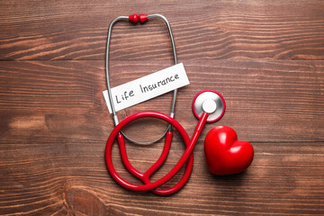 Stethoscope with text LIFE INSURANCE on wooden background