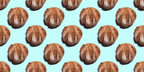 Fresh homemade rustic rye round bread seamless pattern isolated on blue background, top view. Can be used as food background, base for textiles, packaging