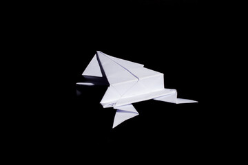 Origami frog made from white paper isolated on black background