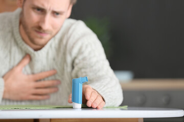 Young man with inhaler having asthma attack at home
