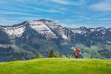 smiling senior woman riding her electric mountain bike on a sunny day in early spring with yello...