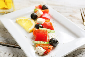 Plate of tasty Greek salad on wooden table, closeup