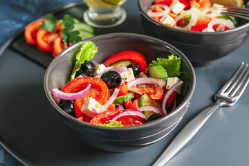 Bowls of tasty Greek salad on table