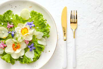 Plate with fresh lettuce and flowers on light background, closeup