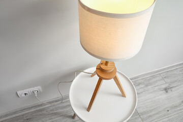 Stylish glowing lamp on table in room
