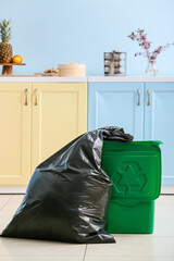 Bag with garbage and rubbish bin with logo of recycling at home