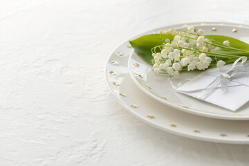 Beautiful table setting with lily-of-the-valley flowers on light background