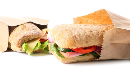 Bags with tasty ciabatta sandwiches on white background