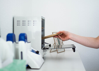 A young woman puts the manicure tools in a dry oven for disinfection. Professional wax heater and professional dry oven disinfection of manicure tools.