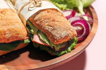 Plate with tasty ciabatta sandwiches on color background
