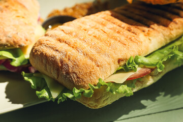 Plate with tasty ciabatta sandwiches on color wooden background