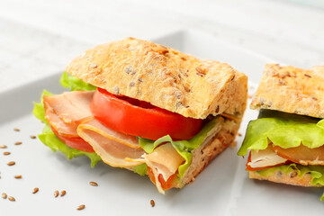 Plate with tasty ciabatta sandwich on light wooden background