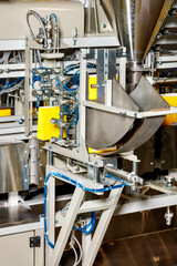 Detail of a production line in the food industry for packaging bulk products in yellow paper bags.