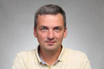 Obraz premium A handsome man in a pastel yellow shirt in the studio looks at the camera.