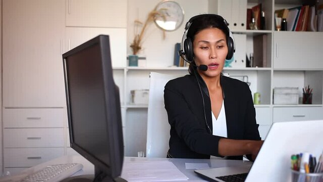 Young woman call centre operator with headphones during working in modern office . High quality FullHD footage