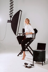 A beautiful woman photographer works in a professional photo studio among the lighting equipment....