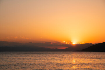 Beautiful golden sunset over the lake. The summer sun goes down behind the mountains.