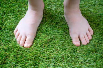 Tender kid legs close-up on the soft artificial grass