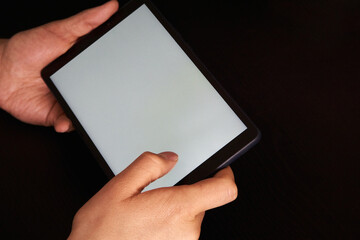 A person playing with his tablet with a white screen, ready to place any design on a black background