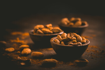 Organic cocoa beans in small bowls on brown background